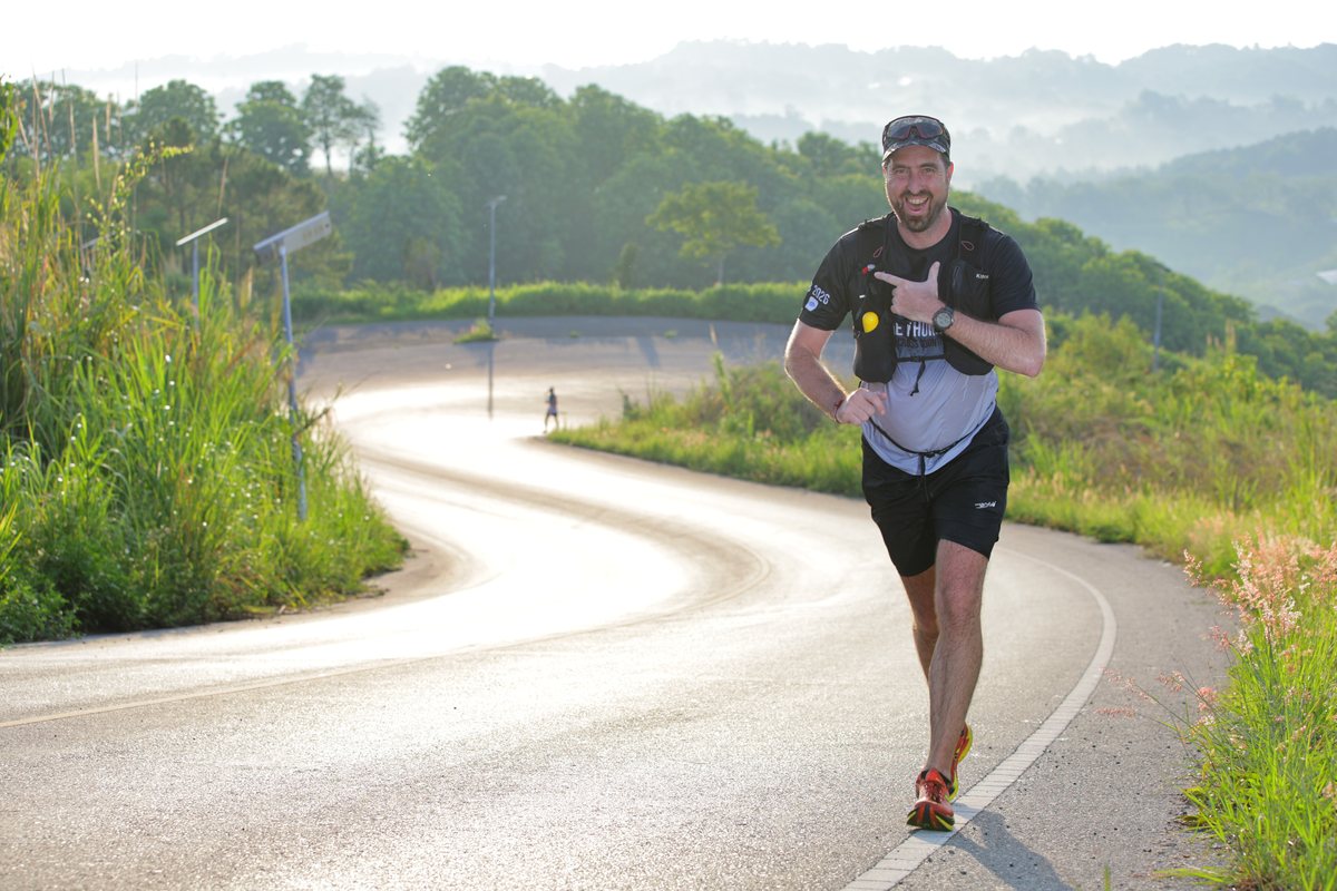 Jef mid-race at a trail run, pointing at his watch