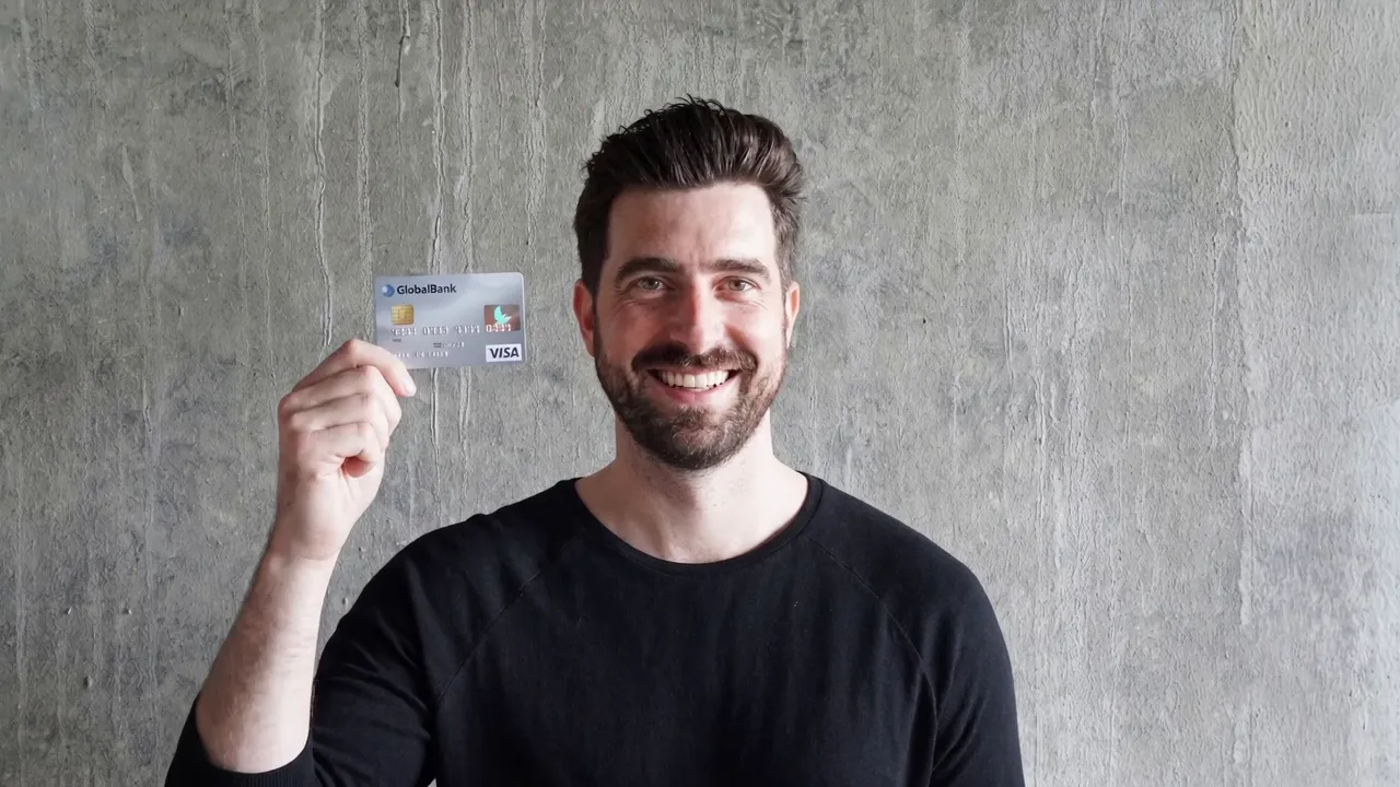 The same man, alive and grinning, holding up a credit card